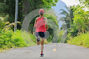 Woman running on morning tropical forest trail