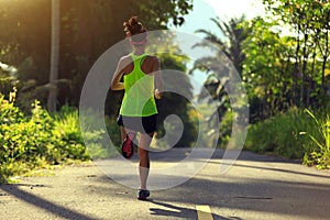 Woman running on morning tropical forest trail