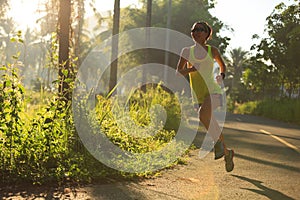 Woman running at morning tropical forest trail