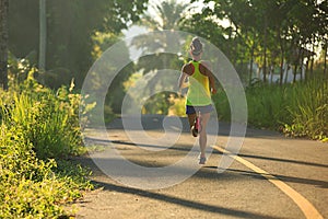 Woman running on morning tropical forest trail