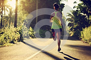 woman running on morning tropical forest trail