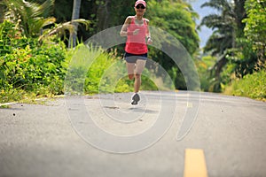 woman running at morning tropical forest trail