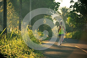 Woman running on morning tropical forest trail