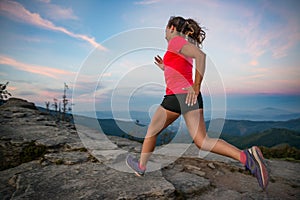 Woman running on rocks. Female cross country running in mountains.