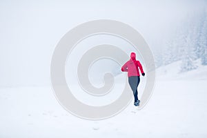 Woman running on snow in winter mountains