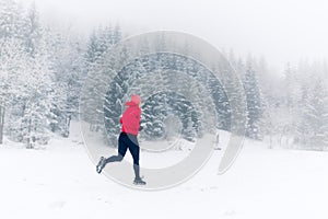 Woman running on snow in winter mountains