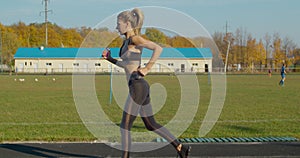 Woman running at a stadium in sunny day.