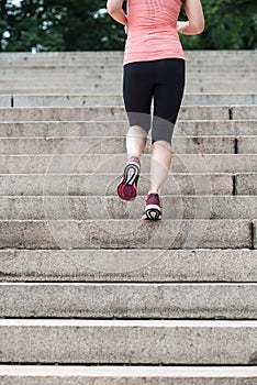 Woman running on steps in New York Central Park wearing sport clothes at summer time