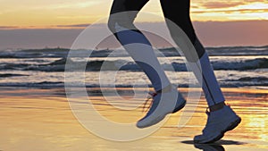 Woman running on sunset beach. Sport footwear, wet sand footprints