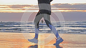 Woman running on sunset beach, wet sand footprints