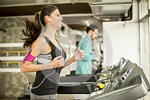 Woman running on the treadmill and listening to music at t