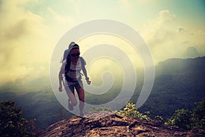 Woman running up on mountain top cliff edge