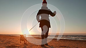 Woman running, walking, playing and having fun with her doggy at sunset on a beach near Baltic sea in spring. Colorful