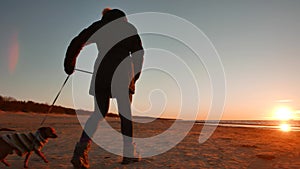 Woman running, walking, playing and having fun with her doggy at sunset on a beach near Baltic sea in spring. Colorful