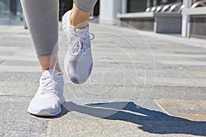 Woman running with white shoes in the city, sunny day