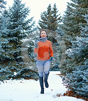 Woman is running in winter forest, beautiful landscape with snowy fir trees