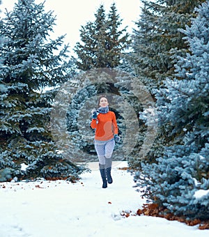 Woman is running in winter forest, beautiful landscape with snowy fir trees