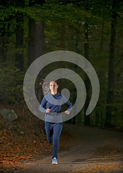 Woman running in wooded forest area, training and exercising for trail run marathon endurance
