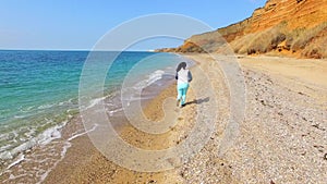 A woman runs along the coastline and the camera follows her.