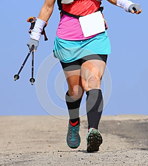 Woman runs with bandage at the knee and with Nordic walking pole