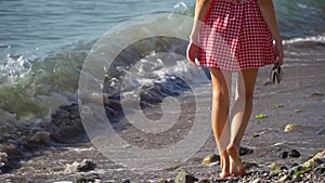 A woman runs barefoot in the water along the beach to the sea. Women feet in the water walk along the shore among the