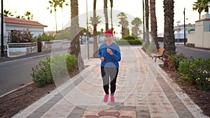 Woman runs down the street along the palm avenue at sunset. Healthy active lifestyle. Video was shot at different speeds