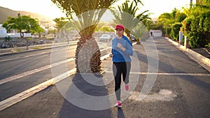 Woman runs down the street among the palm trees at sunset. Healthy active lifestyle