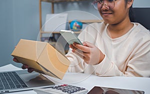 Woman runs an e-commerce business is checking orders from laptop, she owns an online store, she packs and ships through a private