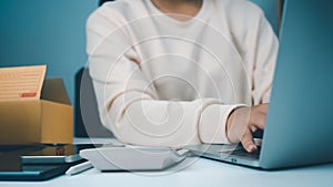 Woman runs an e-commerce business is checking orders from laptop, she owns an online store, she packs and ships through a private