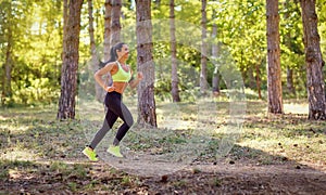 A woman runs through the forest in a jog.