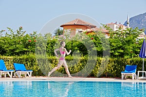 Woman runs at poolside around pool