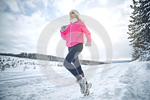 A woman runs in the snow in the winter mountains. Sports, fitness - inspiration and motivation. Woman jogging outdoors.