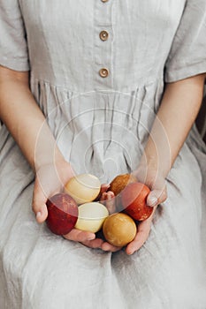 Woman in rustic linen dress holding natural dyed easter eggs in hands. Happy Easter. Aesthetic