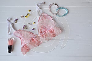 Woman`s accessories on the wooden desk. Beautiful lace lingerie, armlets, flowers and nail polish.