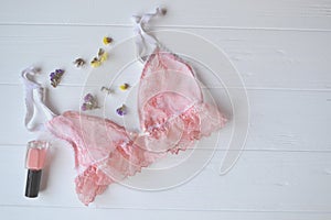 Woman`s accessories on the wooden desk. Beautiful lace lingerie, flowers and nail polish.