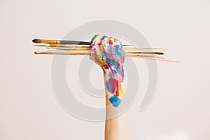 Woman`s artist`s fist in paints with brushes  on a white background. Concept photography for ad or art blog