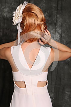 Woman's back view with red hair in retro style,wears elegant white dress