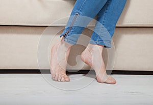 Woman`s bare feet on theheating floor. Legs in jeans sitting on couch. Macro. Copy space and mock up