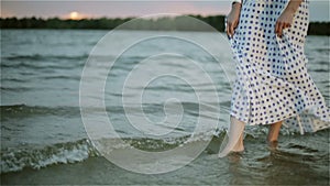 Woman's bare feet in the water of the lake.