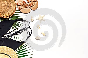 Woman`s beach accessories flat lay. Round trendy rattan bag straw hat black swimsuit leather sandals tropical palm leaves