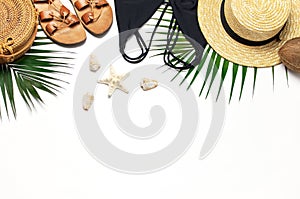 Woman`s beach accessories flat lay. Round trendy rattan bag straw hat black swimsuit leather sandals tropical palm leaves coconut