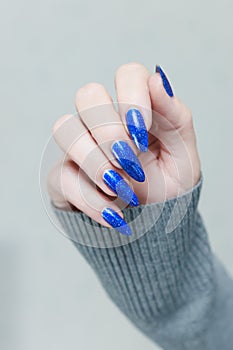Woman\'s beautiful hand with long nails and bright blue manicure