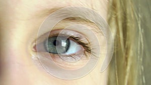 A woman`s blue eyes close-up look to the side and then to the camera, and then blink.Female face of a blonde with golden hair clos