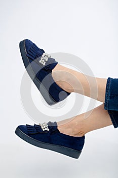 Woman`s blue loafer shoes on female model isolated on white.