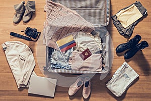 Woman`s clothes, laptop, camer, russian passport and flag of Colombia  lying on the parquet floor near and in the open suitcase. photo
