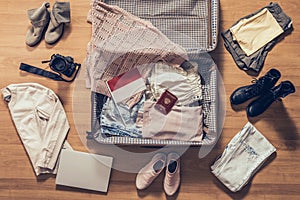 Woman`s clothes, laptop, camer, russian passport and flag of Indonesia lying on the parquet floor near and in the open suitcase.