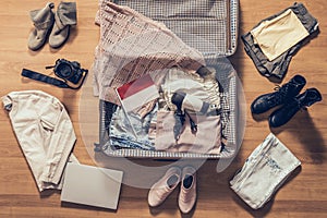 Woman`s clothes, laptop, camer, russian passport and flag of Indonesia lying on the parquet floor near and in the open suitcase.