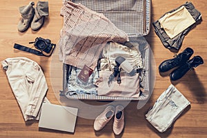 Woman`s clothes, laptop, camera and russian pasport  lying on the parquet floor near and in the open suitcase. Travel photo