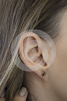 A woman& x27;s ear in close-up. Ear without lobe, earlobe type. Attached earlobes.