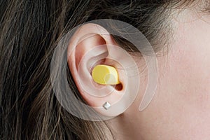 Woman`s ear with an ear plug, noice reduce, noice pollution